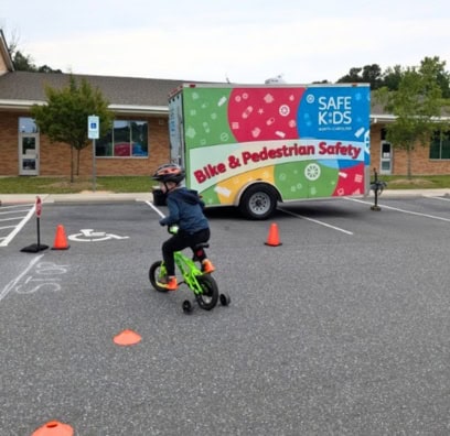 A child riding a bike with training wheels, completing a safety course.